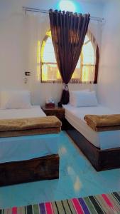 two beds in a room with a window at Sama Stars Hotel in Abu Simbel