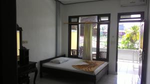 a bedroom with a bed and a window with a balcony at Raditia Homestay in Ubud