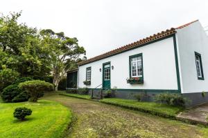 une maison blanche avec une porte verte et une cour dans l'établissement Casa das Duas Ribeiras, à Furnas