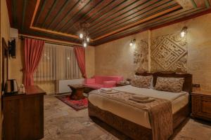 1 dormitorio con 1 cama grande y 1 sofá rosa en Feel Cappadocia Stone House, en Göreme