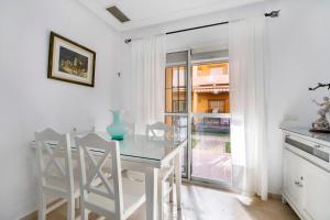 Apartamento Altamar في نوفو سانكتي بيتري: غرفة طعام بيضاء مع طاولة وكراسي زجاجية