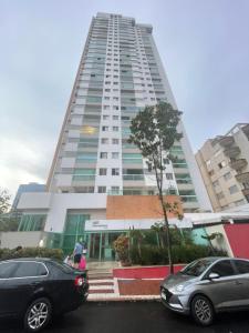dois carros estacionados em frente a um prédio alto em Gift Home Residence 6ºAndar Setor Oeste em Goiânia