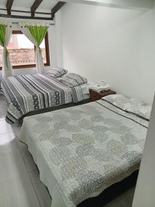 2 nebeneinander sitzende Betten in einem Schlafzimmer in der Unterkunft Hostal Villa Rosita in Villa de Leyva