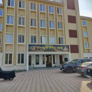 a large building with cars parked in a parking lot at ISKCON'S GITANAGARI RETREAT CENTER VRINDAVAN in Jait