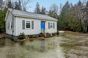 ein kleines weißes Haus mit blauer Tür auf einem Grundstück in der Unterkunft Blue Button Cottage in Gouldsboro