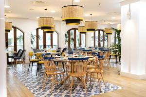 a dining room with tables and chairs and windows at HD Parque Cristobal Tenerife in Playa de las Americas