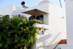 a white building with a window with an umbrella at HD Parque Cristobal Tenerife in Playa de las Americas