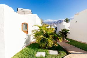 a white house with a palm tree in the yard at HD Parque Cristobal Tenerife in Playa de las Americas