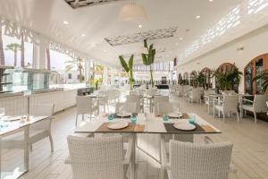 a dining room with white tables and chairs at HD Parque Cristobal Tenerife in Playa de las Americas