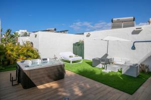 a backyard with a hot tub and an umbrella at HD Parque Cristobal Tenerife in Playa de las Americas