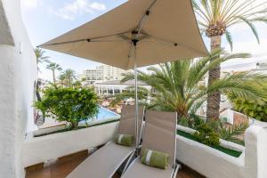 a balcony with two chairs and an umbrella at HD Parque Cristobal Tenerife in Playa de las Americas