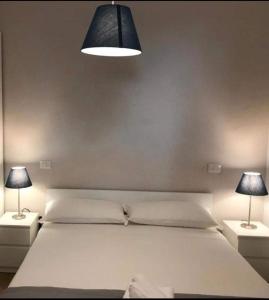 1 dormitorio con 1 cama blanca grande y 2 lámparas en Sant'Elia Country Village, en SantʼAgata di Militello