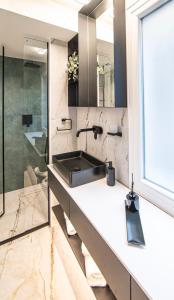 Almasi Luxury Suites Marquise في أليكساندروبولي: حمام مع حوض ومرآة