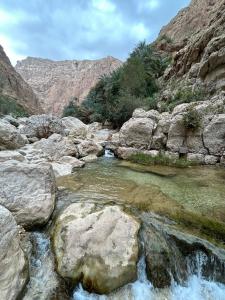 a river in a mountain with rocks and water at Atlas Wadi Shab in Sur