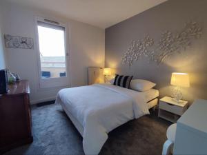 una camera da letto con un letto bianco e una finestra di LE DUPLEX DU MARCHÉ a Châteauroux