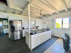 a kitchen with white cabinets and a stainless steel refrigerator at Duplex Ti Rooftop spa et vue mer in Saint-Leu