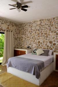 a bedroom with a bed and a stone wall at Casa Ixtzá in Nimá