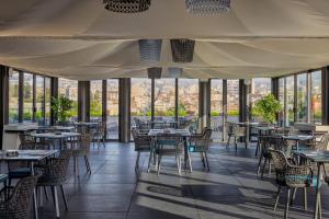 um restaurante com mesas, cadeiras e janelas em Palace Catania | UNA Esperienze em Catânia