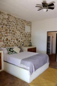Un dormitorio con una pared de piedra y una cama en Casa Ixtzá, en Nimá