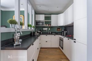 une cuisine avec des armoires blanches et des comptoirs noirs dans l'établissement REPUBLIQUE Plein centre historique et à 2 pas de la grande plage, à Saint-Jean-de-Luz 8 autres photos