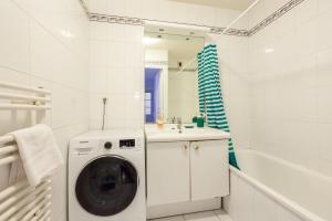 ein weißes Badezimmer mit einer Waschmaschine und einem Waschbecken in der Unterkunft Spacious 1BR | Near City Center & Baby-Friendly! in Lyon