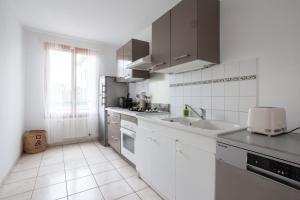 eine weiße Küche mit einem Waschbecken und einem Fenster in der Unterkunft Spacious 1BR | Near City Center & Baby-Friendly! in Lyon