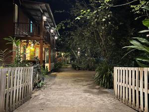 Una casa con una valla y una pasarela por la noche en Baan rabiang Pai บ้านระเบียงปาย, en Pai