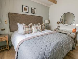 a bedroom with a large bed and a mirror at Orton Cottage in Appleby