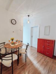 a room with a table and chairs and a clock on the wall at Apartment Libar with Terrace and private Parking in Mostar