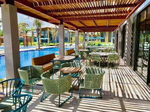 un patio con mesas y sillas junto a una piscina en Refúgio em Condomínio- Flecheiras en Trairi