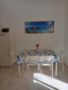 a dining room table with chairs and a painting on the wall at Victoria apartments in Lampedusa