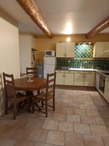 a kitchen with a table and chairs and a sink at Mas de la fontaine in Lafarre