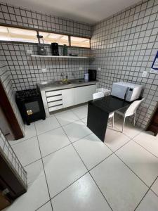 Casa aconchegante em Guadalupe/PE في Sirinhaém: مطبخ فيه طاولة سوداء وكراسي