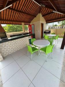 Casa aconchegante em Guadalupe/PE في Sirinhaém: فناء به طاولات وكراسي خضراء في مطعم