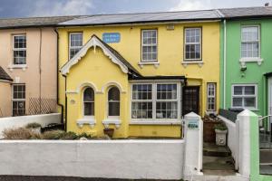 a yellow and green house with a fence at Sea View Cottage, Sandgate in Sandgate