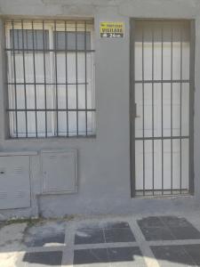 a white building with a door with bars on it at Departamento Temporario Bianchi in Santiago del Estero