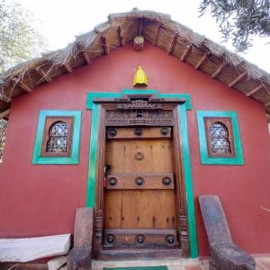 a red house with a wooden door with a bell on top at Manzal Lahbab, 2Villas 2Bungalows 2Piscines et Jardins in Marrakech +83 photos