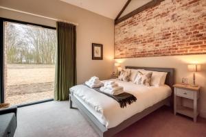 a bedroom with a bed and a brick wall at Downs in Blewbury