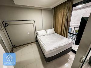 a small bed in a room with a balcony at Studio na Av. Oceânica House Barra in Salvador