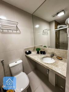 a bathroom with a toilet and a sink and a mirror at Studio na Av. Oceânica House Barra in Salvador