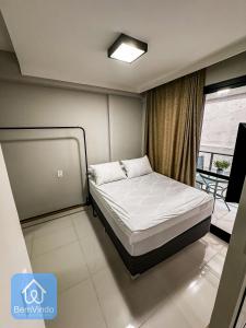 a bedroom with a bed in a room with a window at Studio na Av. Oceânica House Barra in Salvador
