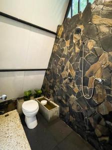 een badkamer met een toilet en een stenen muur bij Oasis forest garden in Ban Takuk Nua