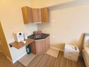 a small kitchen with a sink and wooden cabinets at Cebu Avida Riala T4 2320 IT Park in Cebu City