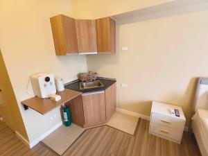 Elle comprend une petite cuisine avec un évier et des placards en bois. dans l'établissement Cebu Avida Riala T4 2320 IT Park, à Cebu