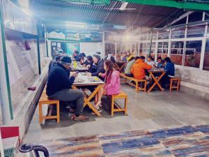 um grupo de pessoas sentadas em mesas em um restaurante em Himalayas Youth Hostel Kempty Mussoorie em Mussoorie