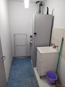 a small bathroom with a sink and a refrigerator at El Sarmiento M & L Mendoza in Las Heras