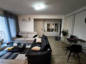 a living room with a black leather couch and a table at Chez Jean-Claude, vue panoramique au réveil in Poitiers