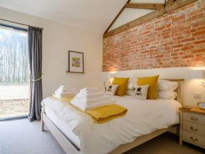 a bedroom with a white bed with a brick wall at Gallops in East Ilsley