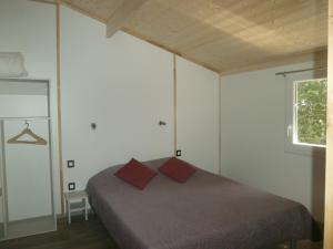 een slaapkamer met een bed met 2 rode kussens bij Gites Les Chrisalies in Pont-Saint-Esprit