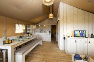 a large kitchen with white cabinets and a table at Camping USHUAÏA Villages Au Bois Joli in Andryes